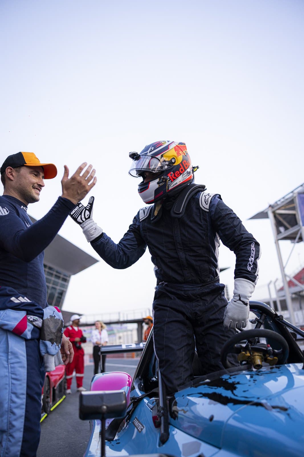 Marcel Kiefer in race suit and helmet high-fiving a teammate beside the car