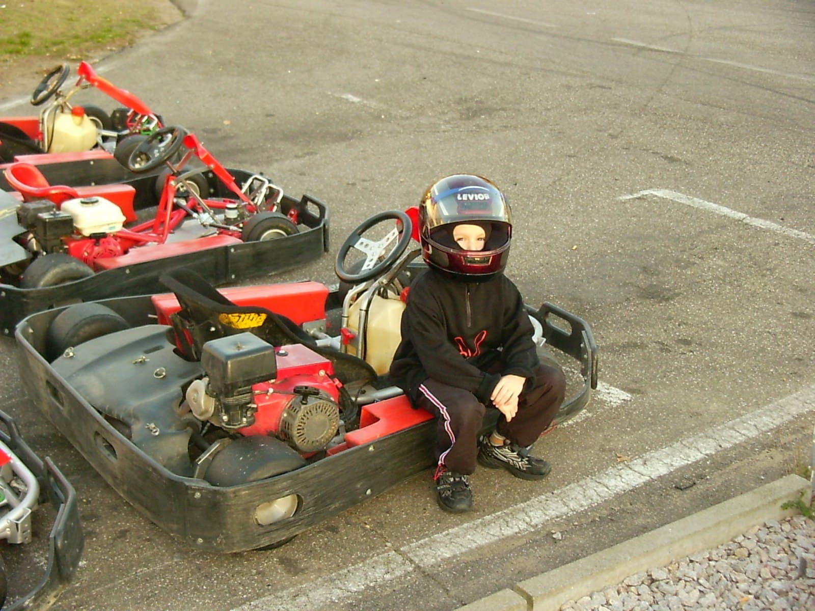 Marcel as a child sitting on a rental kart, helmet on