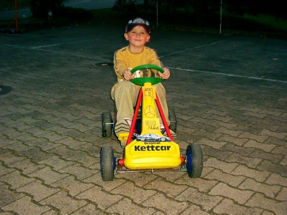 Marcel as a small child on a yellow Kettcar pedal kart